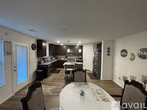 A dining room with a table set for two and a kitchen area in the background.