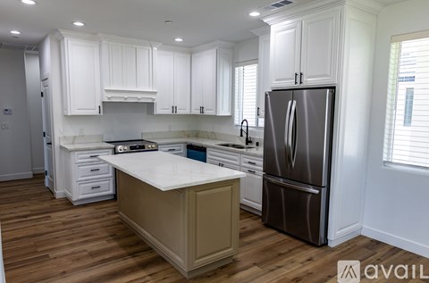 A kitchen with white cabinets and a wooden island.