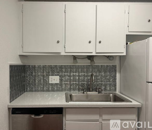 A kitchen with white cabinets and a silver dishwasher.