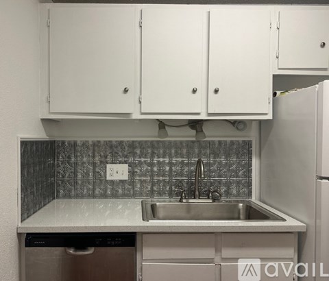 A kitchen with white cabinets and a silver dishwasher.