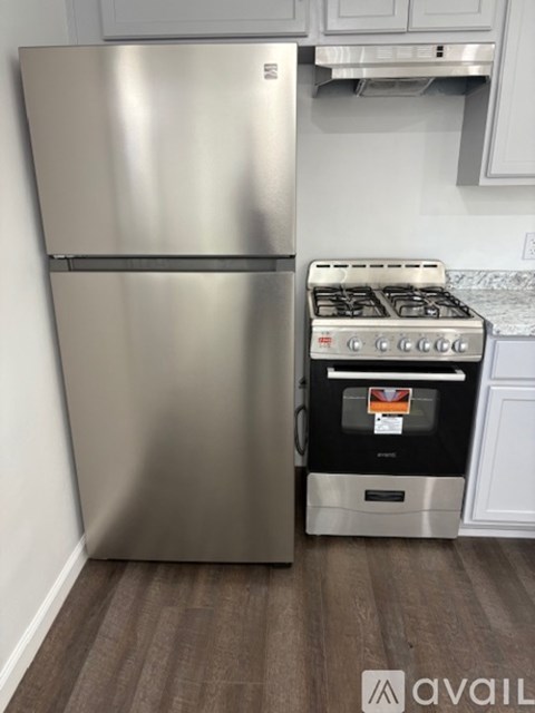 A stainless steel refrigerator stands next to a stove in a kitchen.