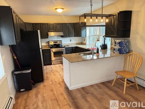 A kitchen with a black refrigerator and wooden floors.
