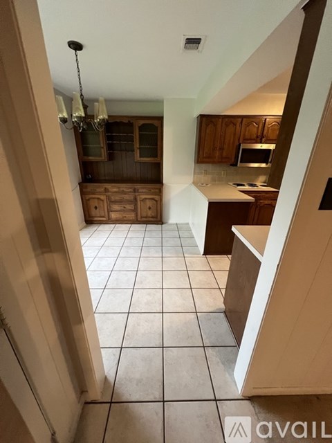 A kitchen with a white tiled floor and wooden cabinets.
