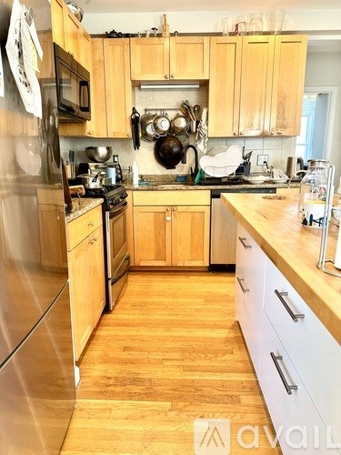 A kitchen with wooden cabinets and a stainless steel refrigerator.