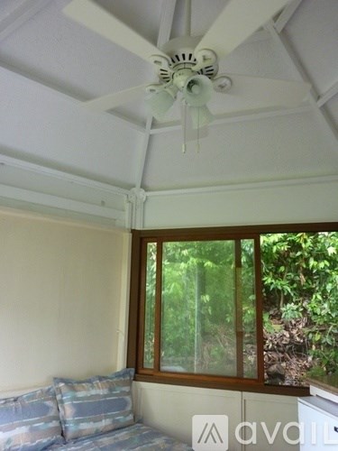A white ceiling fan in a room with a window.
