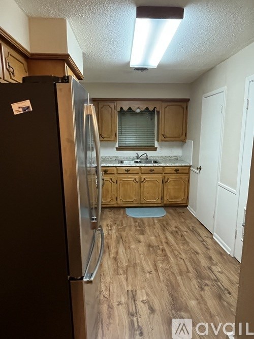 A kitchen with a black fridge and wooden cabinets.