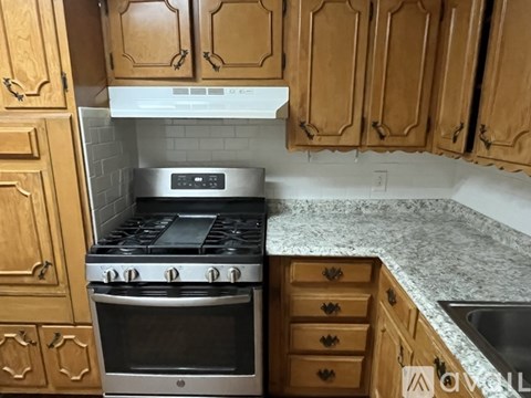 A kitchen with wooden cabinets and a stainless steel oven.