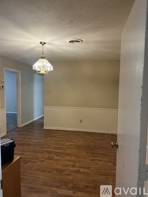 A room with wooden floors and a chandelier hanging from the ceiling.