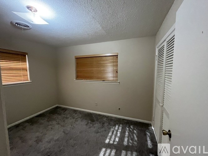 A room with a fan on the ceiling and a window with blinds.