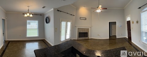 A large, empty living room with a fireplace and a marble countertop.
