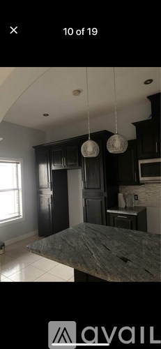 A kitchen with dark cabinets and a marble countertop.