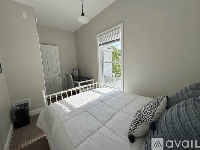 A bedroom with a large bed and a window overlooking a tree.