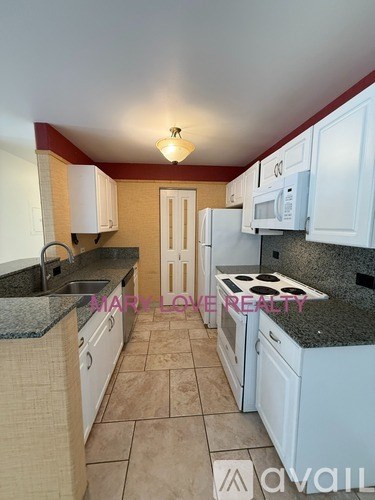 A kitchen with white cabinets and a granite countertop.