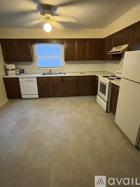 A kitchen with brown cabinets and white appliances.