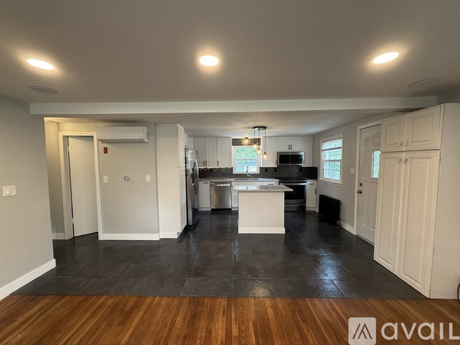 A spacious kitchen and dining area with wooden flooring and white walls.