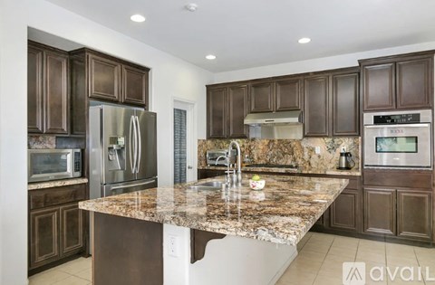 A kitchen with brown cabinets and granite countertops.