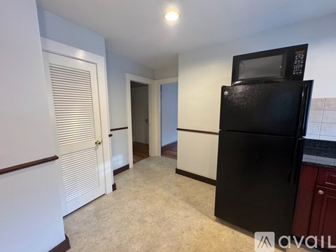 A black refrigerator is in a kitchen with a white door and a white counter.