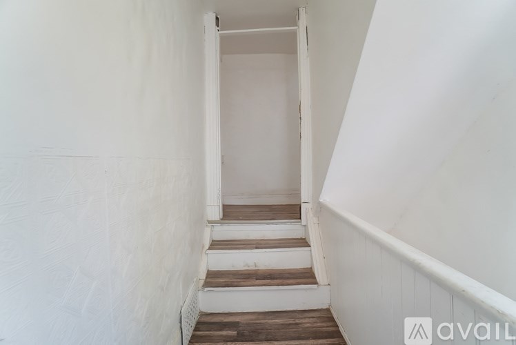 A stairway with wooden steps and white walls.