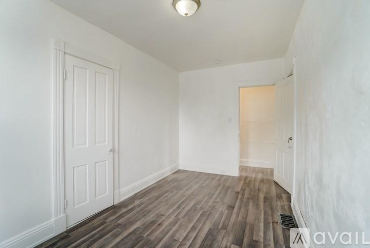 A room with wooden flooring and white walls.