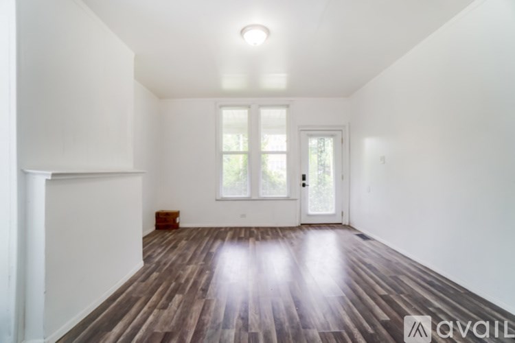 A room with wooden floors and white walls is available for rent.