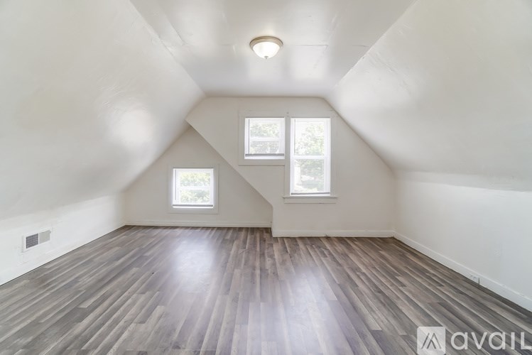 A room with wooden flooring and two windows.