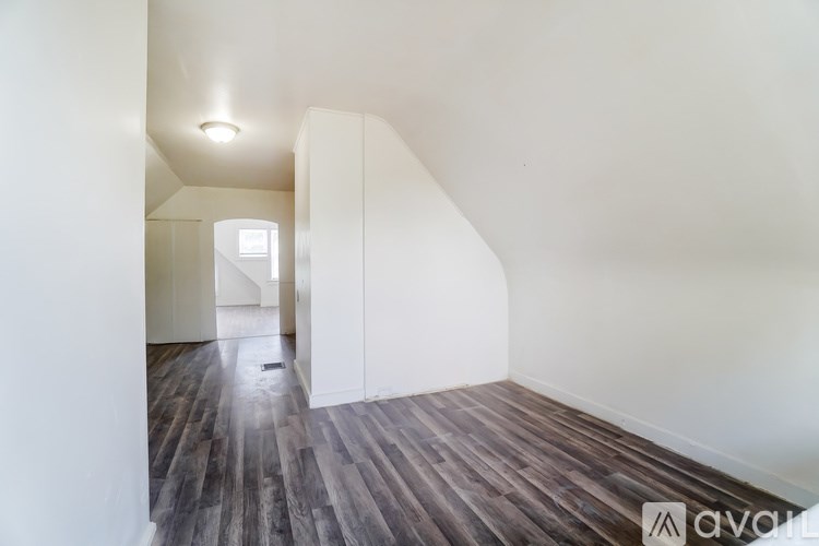 A hallway with wooden floors and white walls.
