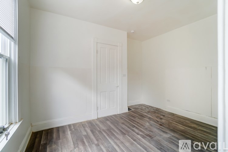 A room with wooden flooring and a white door.