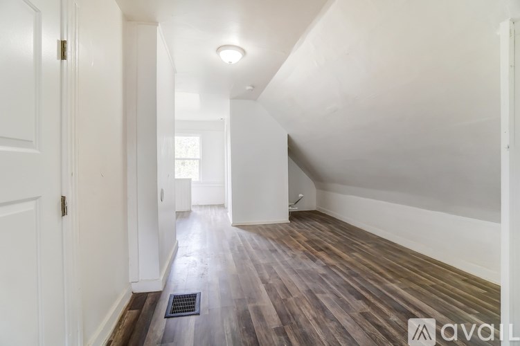 A hallway with wooden floors and white walls.