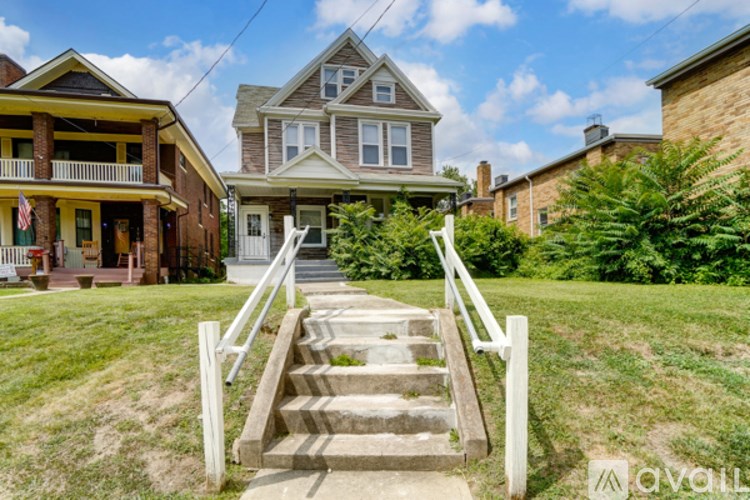 A house with a front yard and a staircase leading to the front door.