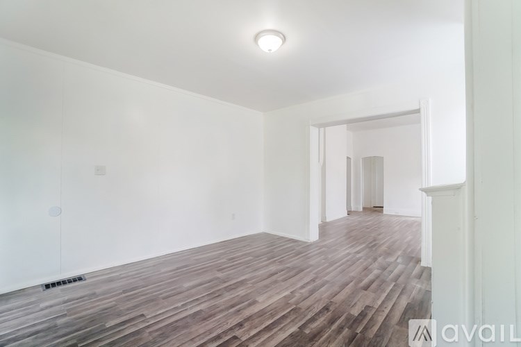 A room with wooden flooring and white walls.