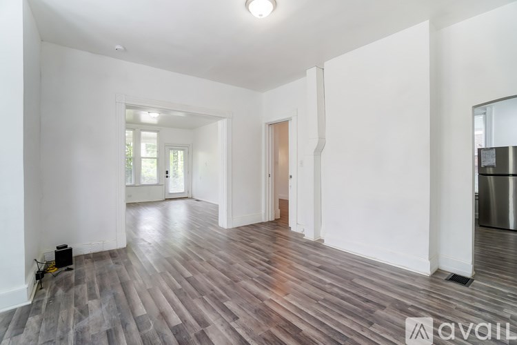 A spacious room with wooden flooring and white walls.