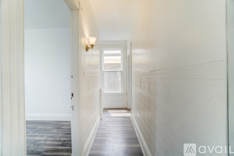 A long hallway with a door on the left and a window on the right.
