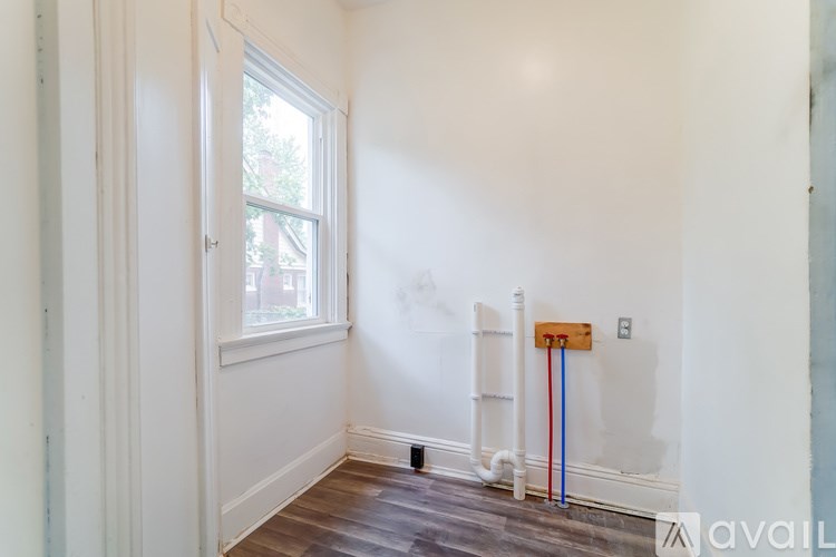 A room with a window and a white wall with a pipe and a tape measure.