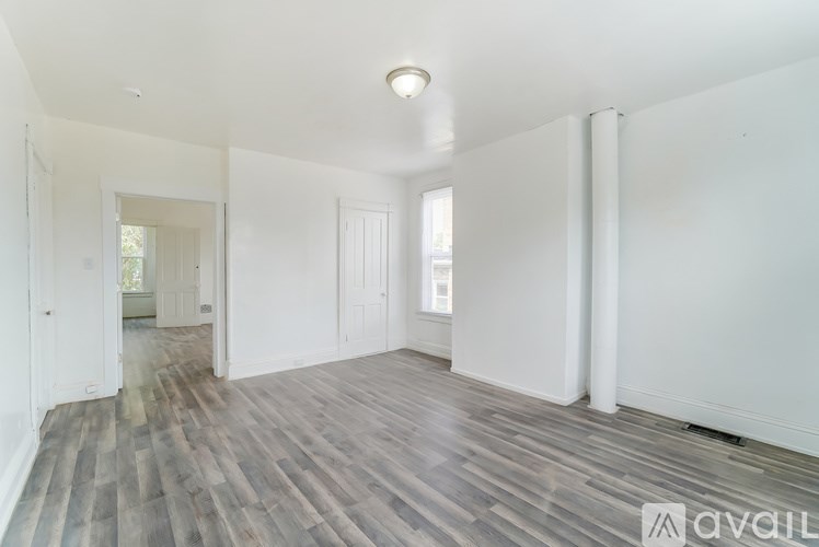 A spacious room with wooden flooring and white walls.