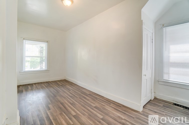A room with wooden flooring and a window with blinds.