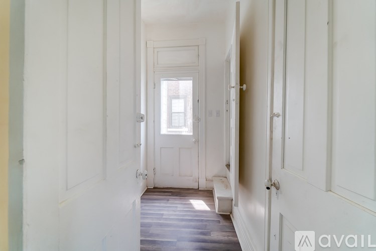 A long hallway with white walls and a wooden floor.