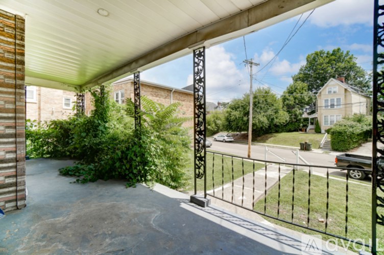 A view from a covered walkway looking out to a street with cars and houses.