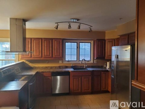 A kitchen with wooden cabinets and a stainless steel refrigerator.