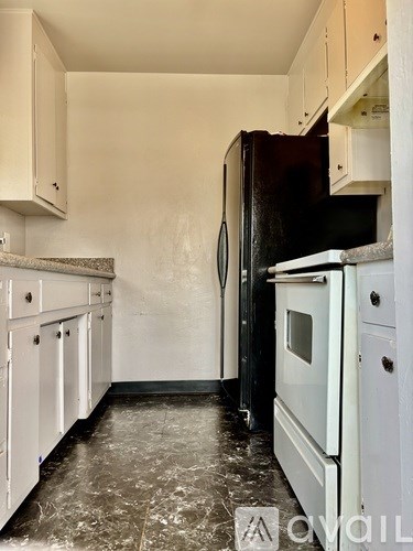 A kitchen with a black refrigerator and white cabinets.