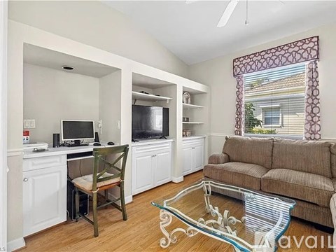 A living room with a brown couch and a glass coffee table.
