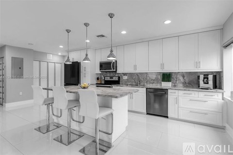 A modern kitchen with white cabinets and a marble countertop.