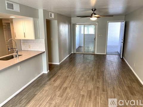 A spacious room with wooden flooring and a ceiling fan.