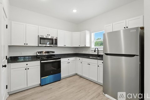 A kitchen with white cabinets and a stainless steel refrigerator.