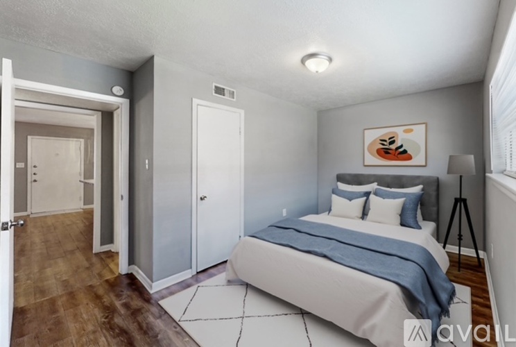 A bedroom with a bed, a painting, and a tripod.