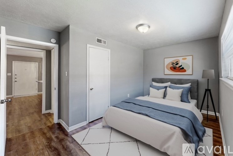 A bedroom with a bed, a painting, and a tripod.