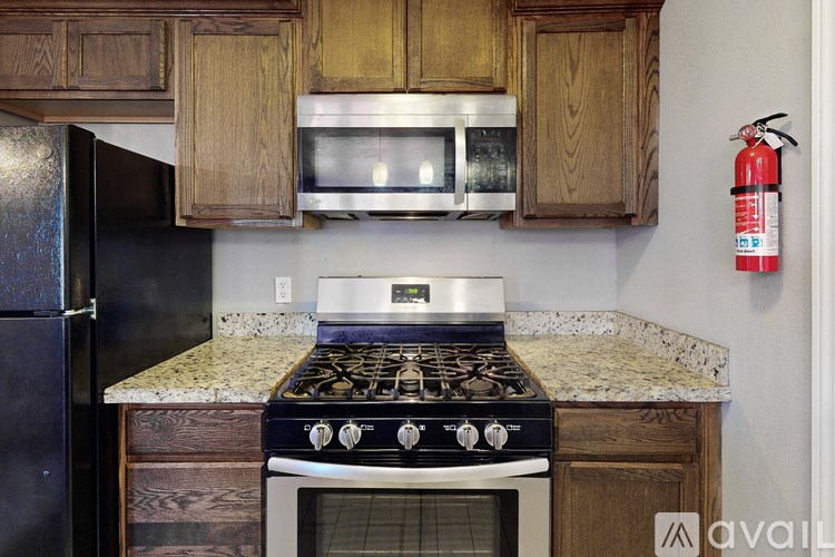 A kitchen with a black fridge, a white stove and wooden cabinets.
