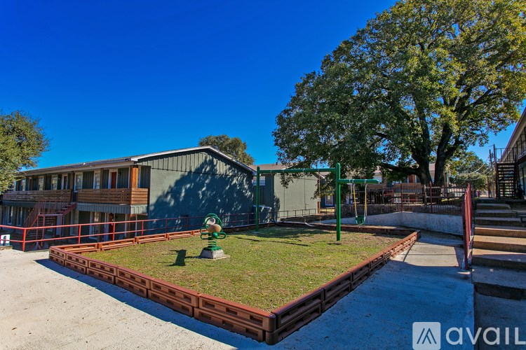 A playground with a green slide and a red fence.