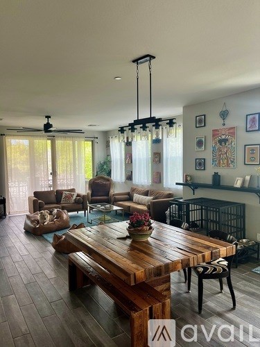 A living room with a wooden table and chairs, a couch, and a ceiling fan.