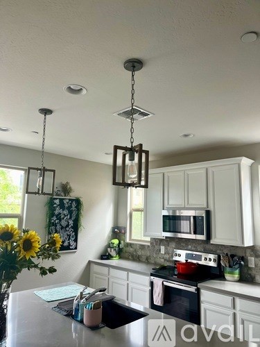 A kitchen with a white counter top and a hanging light fixture.