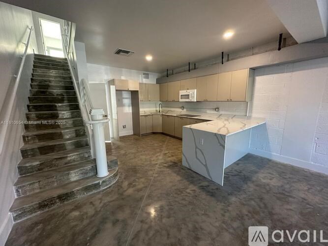 A spacious kitchen and living room with a staircase on the left side.